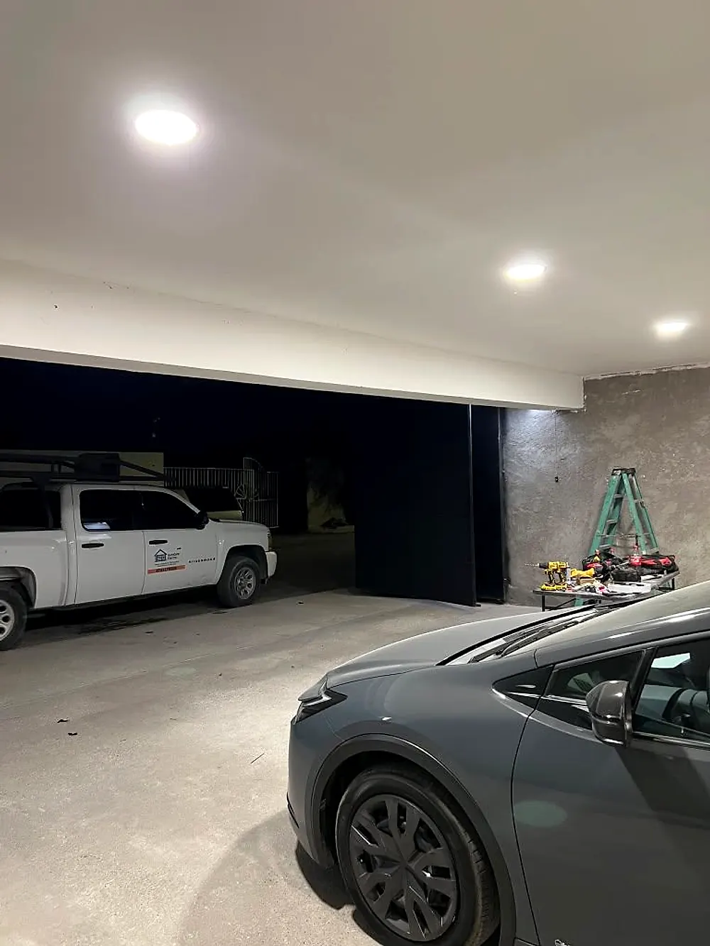 Portón metálico negro instalado en cochera iluminada de noche