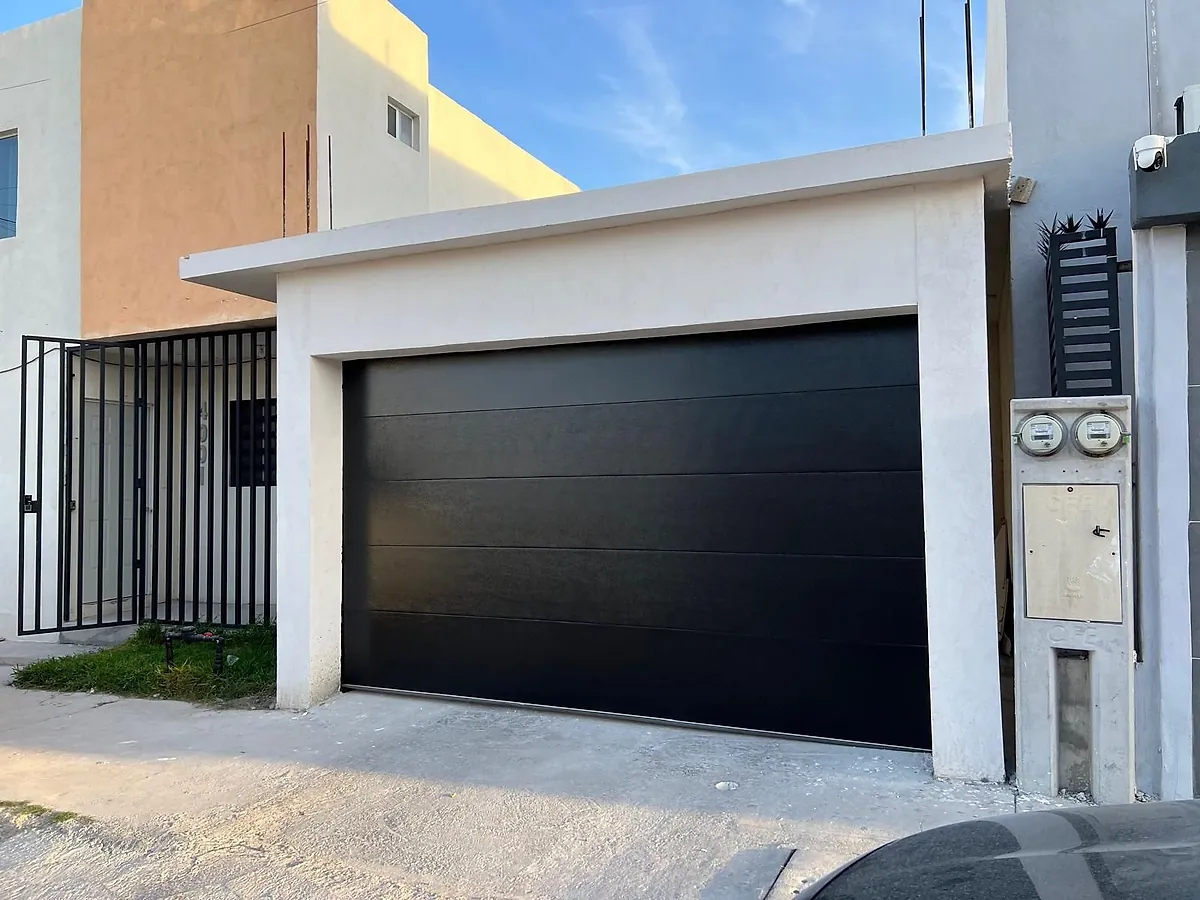 Portón americano negro instalado en una cochera residencial